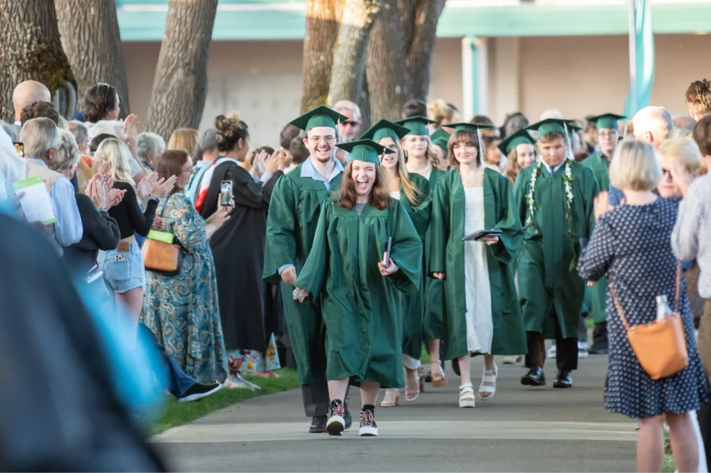 Group of students walking in cap and gowns, smiling
