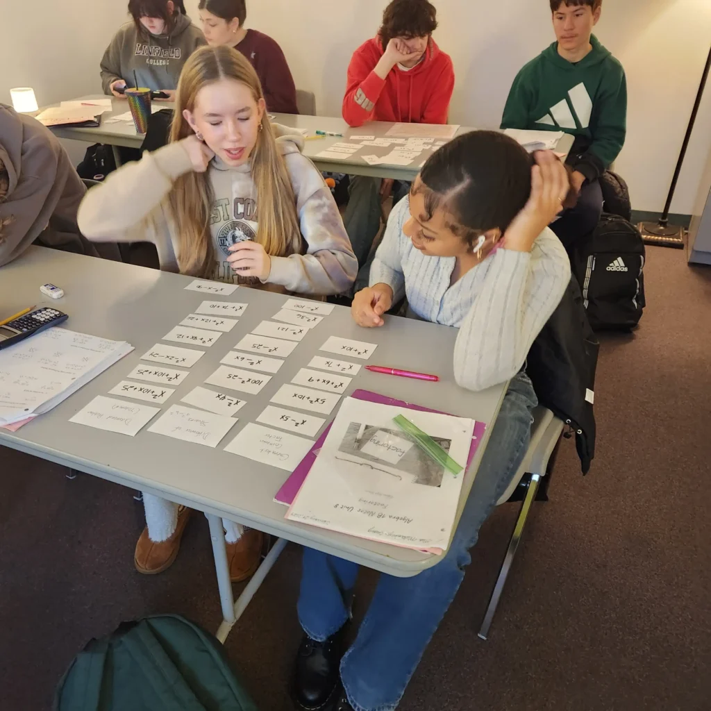 Two students seated at a desk with flash cards