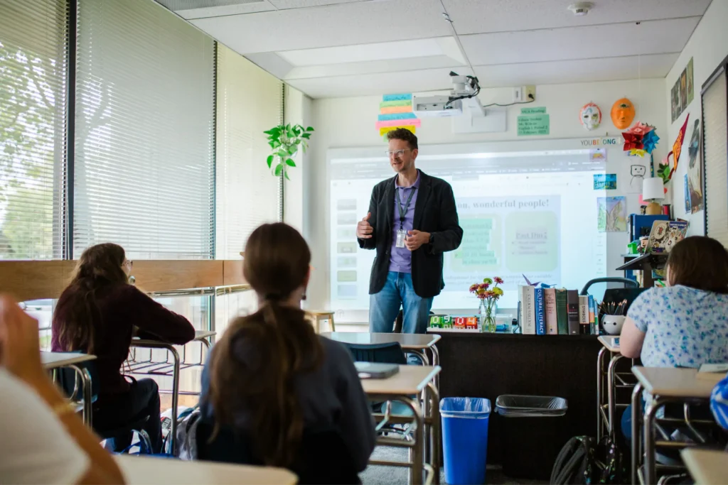 Teacher speaking in front of students seated at their desks