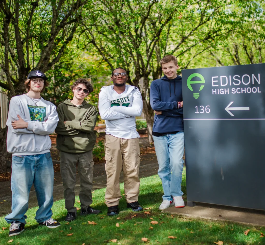 Four students, arms crossed, standing next to Edison Highschool address sign.